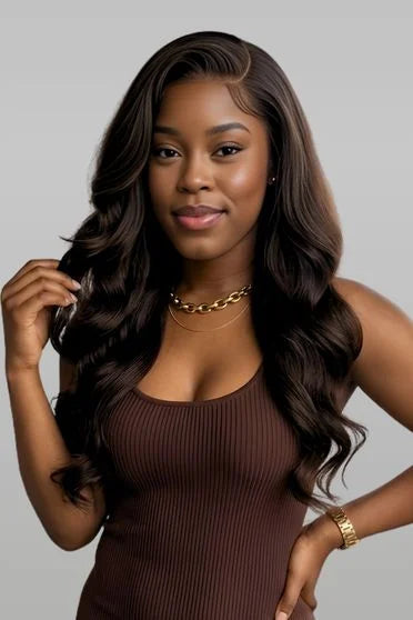 Woman with long, wavy hair wearing a brown top against a gray background